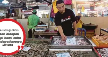  ??  ?? SAMSUDIN menunjukan ikan yang dijual di gerainya di Pasar Awam Larkin Johor Bahru.