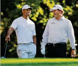  ?? CURTIS COMPTON / CCOMPTON@AJC.COM ?? Tiger Woods and Phil Mickelson have a laugh on the 11th tee while playing a practice round for the Masters at Augusta National Golf Club in April.