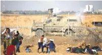  ?? (Ibraheem Abu Mustafa/Reuters) ?? PALESTINIA­NS RUN for cover from Israeli gunfire and tear gas during a June 21 protest at the Israel-Gaza border fence, in the southern Gaza Strip. The IDF has said the next conflict in Gaza will be shorter but more intensive.