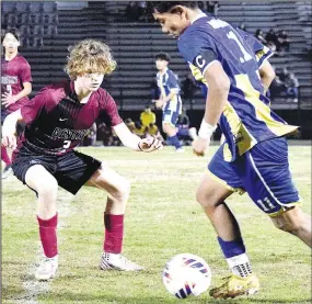  ?? Ariana Kumbera/Special to the Eagle Observer ?? A Pioneer player tries to block the way as Bulldog Robert “T” Thang (right) moves the ball downfield during the Gentry-Decatur varsity boys’ soccer match at Pioneer Stadium in Gentry on Feb. 27. The Bulldogs claimed the victory, 3-1, over the Pioneers.