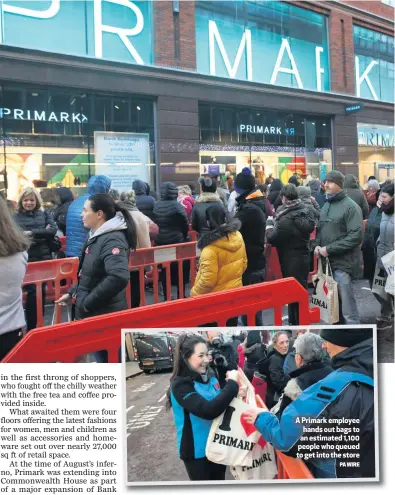  ?? PA WIRE ?? A Primark employee hands out bags to an estimated 1,100 people who queued to get into the store