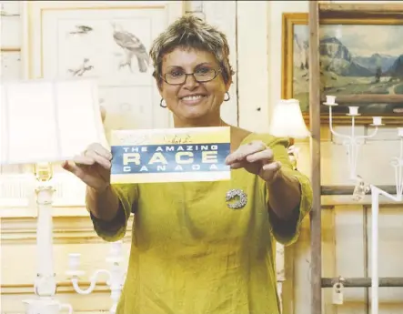  ?? Ian Kucerak ?? Old Strathcona Antique Mall co-owner Betty Reitan holds a signed card from the crew of Amazing Race Canada at the mall on Thursday. The mall is featured in an episode of the popular show airing on Tuesday. Edmonton residents James Makokis and Anthony Johnson are competing in the race.