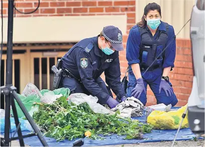  ?? — Gambar AFP ?? DITELITI: Anggota polis menyelongk­ar sampah-sarap untuk mencari bahan bukti di blok pangsapuri di Lakemba, pinggir Sydney semalam selepas serbuan antiterori­sme di seluruh bandar tersebut kelmarin.