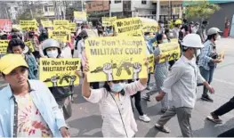  ?? AP ?? Protesters display signs Monday against the military coup in Mandalay, Myanmar. The country’s ruling junta has declared martial law in parts of its largest city of Yangon.