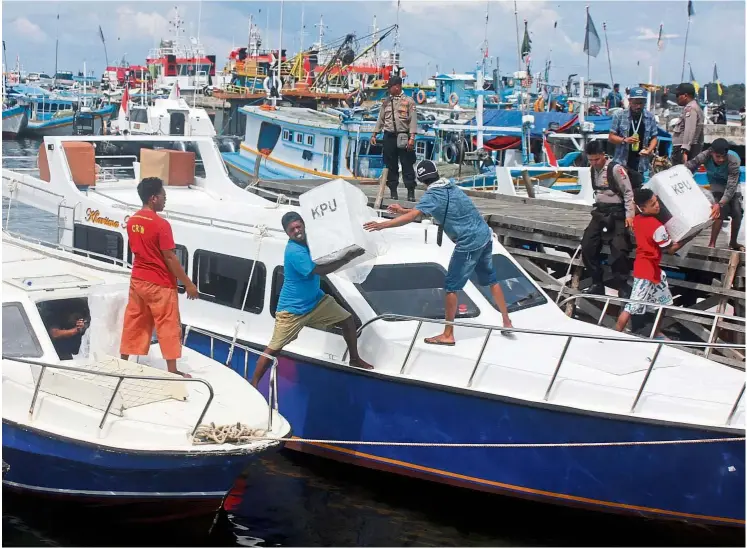  ?? — Reuters ?? Workers loading election material into a boat to be distribute­d in Sorong, West Papua, Indonesia.