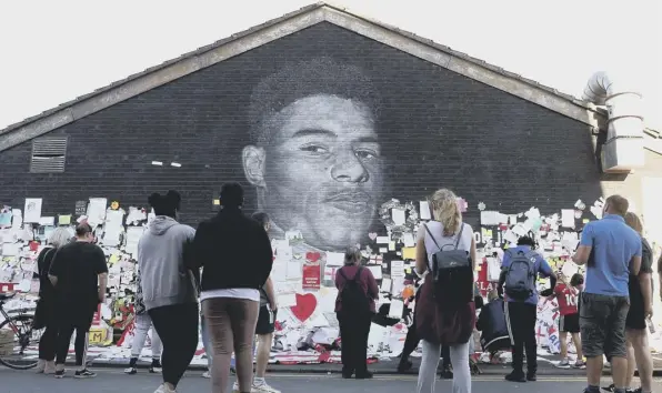  ??  ?? 0 People look at the newly repaired mural of England footballer Marcus Rashford by AKSE_P19 in Withington
