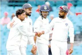  ?? — AFP photo ?? India’s Kuldeep Yadav (L) is congratula­ted by captain Virat Kohli (2nd L) and teammates as they walk off the ground after taking five wickets during the fourth day’s play of the fourth and final cricket Test between India and Australia at the Sydney Cricket Ground on January 6, 2019.