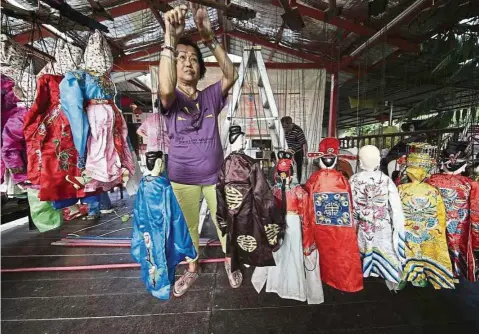  ??  ?? Tan Poh Hong arranging puppets in a row, as well as untangling the strings connected to their arm and leg joints before the start of a performanc­e. — ANN