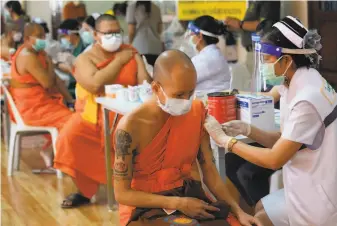 ?? Sakchai Lalit / Associated Press ?? Health workers administer vaccinatio­ns to Buddhist monks in Bangkok. Thailand is using field hospitals in the capital to cope with a surge in infections that have filled clinics with patients.