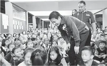  ??  ?? Dennis spends time with the schoolchil­dren. Behind him is SK Long Bedian headmaster Jenggo Jau Jok.