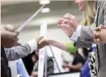  ?? — Reuters ?? Corporate recruiters (R) gesture and shake hands as they talk with job-seekers in Washington.