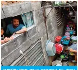  ??  ?? BANGKOK: Photo shows motorcycle taxi driver. Thanapat Noidee with son Kittipat looking from the window of their home in Bangkok. — AFP