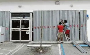  ?? Joe Raedle/afp ?? Trabalhado­res colocam placas nas janelas de um mercado para se preparar para a chegada do furacão Dorian, em Riviera Beach, na Florida