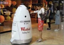  ?? THE ASSOCIATED PRESS ?? Sophie Li, of Cupertino, Calif., offers to dance with a K5 robot made by Knightscop­e Inc., at Westfield Valley Fair shopping center in San Jose, Calif.