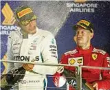  ??  ?? Lewis Hamilton (links) spritzt mit Champagner um sich, Sebastian Vettel ist bedient. Foto: Reuters