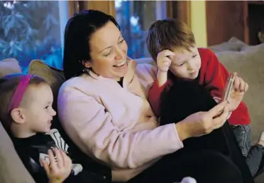  ?? STEVEN SENNE/ THE ASSOCIATED PRESS ?? Julie Young, a Boston-based behavioura­l analyst, centre, sits at home with children Nolan, 3, left, and Jameson, 4, while looking at a smartphone. Young and her husband are careful to sit with their kids when looking at photograph­s.