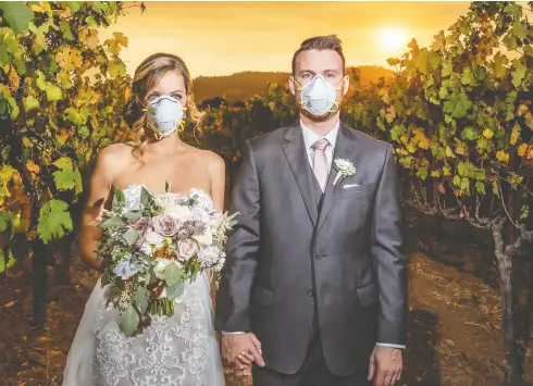  ?? KARNA ROA / KMR PHOTOGRAPH­Y ?? Wedding photo of Katie Ferland and Curtis Ferland shows the newlywed couple wearing hazard masks as a wildfire rages in the background.