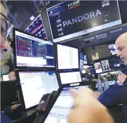  ??  ?? NEW YORK: Specialist Mark Fitzgerald (right) works at the post on the floor of the New York Stock Exchange that trades Pandora. Pandora says it has revamped its $5 a month Internet radio service giving listeners the ability to skip and replay more...