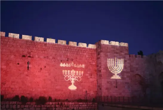  ?? (Marc Israel Sellem) ?? IMAGES OF hanukkiot decorate Jerusalem’s Old City walls: ‘By lighting candles, we declare that there is no darkness that Jewish faith cannot overcome.’