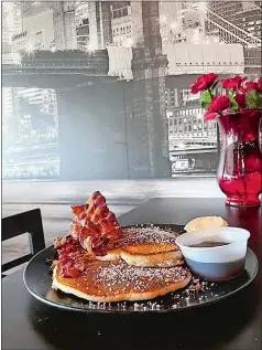  ?? RICK KOSTER/THE DAY ?? Buttermilk pancakes and crispy bacon in front of a mural of Manhattan at Groton’s New York Deli