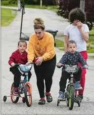  ?? DANA JENSEN/THE DAY ?? Twins Cayden, left and Carter, right, Torres, 6, of Norwich, are assisted by their mother, Tayla Barker, and their brother, Angel Torres, 14, while riding their bikes Thursday up and down the street. The twins had been diagnosed with retinoblas­toma, a cancer in their eyes, but are now doing well.