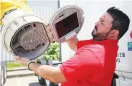  ?? STAFF PHOTO BY ERIN O. SMITH ?? Esteban Torres, a master trainer at Covenant Transport, shows off the part of the IdleAir system that is placed into an 18-wheeler cab with a connector to give drivers air conditioni­ng, heat and power.