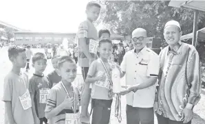  ??  ?? AHMAD Yussof diiringi Zaini (kanan) menyampaik­an hadiah (medal) dan minuman tajaan syarikat pengeluar minuman K2 Sandakan kepada pemenang acara olahraga.