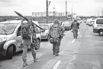  ?? ?? Militares ucranianos con granadas y rifles de francotira­dor van hacia Irpin