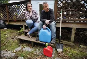  ?? AP PHOTO/ROBERT F. BUKATY ?? Lucinda Tyler and Aaron Raymo sit outside their home Oct. 5 with fuel containers they used to fill their heating oil tank at their home in Jay, Maine.