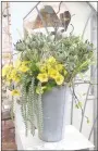  ??  ?? Bright yellow stem flowers and greenery in a metal bucket is one way to bring spring into the home.