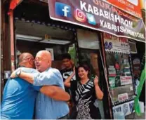  ??  ?? Faisel Shaikh, left, of Ashburn, Virginia, embraces "Bizarre Foods" host Andrew Zimmern, during a chance encounter outside Kababish.