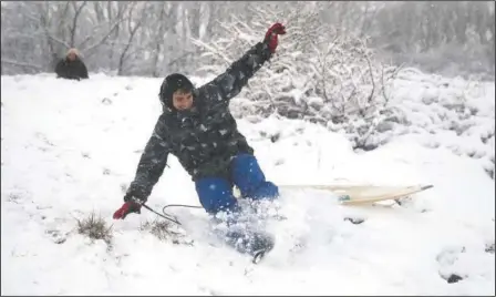  ?? (AP/Andrew Matthews) ?? A man uses a surfboard to sled down a snow-covered hill in Wye National Nature Reserve near Ashford, southern England, on Sunday.