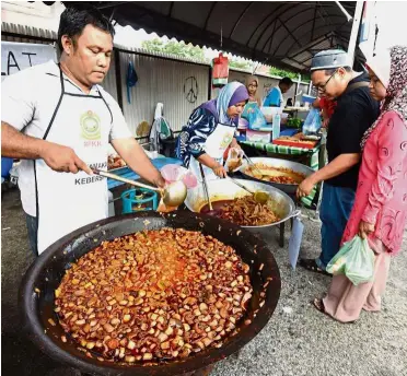  ??  ?? Rare dish: Nasir and his wife Siti Norhaliza selling the ‘Gulai Kawah Batang Pisang’ at the Bazaar Ramadan in Seberang Jaya.