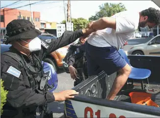  ?? JOSE CABEZAS / REUTERS ?? Police officers guard an alleged leader of a gang after he was presented to the media in San Salvador, El Salvador, on Tuesday.