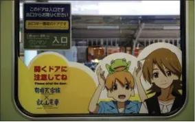  ?? MICHAEL VITO — THE ASSOCIATED PRESS ?? This photo shows characters from the anime series “The Eccentric Family” on a sign on an Eizan Electric Railway train in Kyoto, Japan. Anime tourism is a phenomenon in Japan, with fans hunting down real-world places that are used as settings in the...