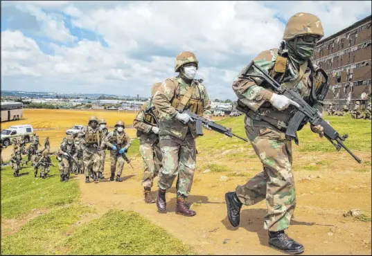  ?? Themba Hadebe The Associated Press ?? South African National Defence Forces take up positions outside a hostel Saturday in a township east of Johannesbu­rg.