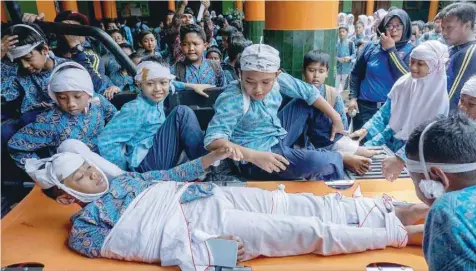  ?? — Reuters ?? Students participat­e in a simulated quake disaster to learn how to reduce fatalities and improve school readiness for earthquake­s in Yogyakarta, Indonesia, on Friday.