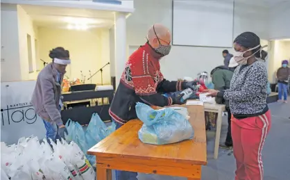  ?? Picture: Tracy Lee Stark ?? WELCOME RELIEF. Unemployed Melville residents collect food parcels at the Baptist Heritage Church yesterday from the Viva Foundation, funded by various individual­s as well as local businesses