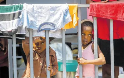  ?? ODELYN JOSEPH ?? Children look through a fence at a shelter for families displaced by gang violence in Port-au-Prince, Haiti, on March 13.