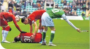  ??  ?? Martin Boyle removes a bottle from the pitch as Borna Barisic lies injured behind him after Ryan Porteous’ tackle