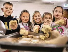  ?? FOTO: RALPH MATZERATH ?? Nico, Fatma, Sarah und Lilly (v. l.) mit dem Teig, den sie gemeinsam angerührt haben. Svenja Holtschnei­der (m.) hat ihnen gezeigt, wie’s geht.