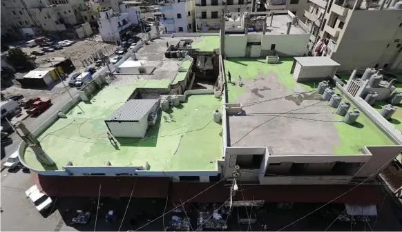  ??  ?? Painters on one of 85 rooftops in Tripoli’s Syria Street, which separates the Sunni neighbourh­ood of Bab Al Tabbaneh from Alawite Jabal Mohsen