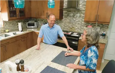  ?? MARTA LAVANDIER/AP ?? Mark Bendell, looking to retire by year’s end, talks with his wife, Laurie, on Monday in their kitchen in Boca Raton, Florida.