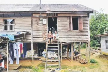  ??  ?? Jimmy and her mother sitting on the staircase of their dilapidate­d house at Kampung Remun, some 10km from Serian yesterday.