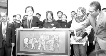  ??  ?? Christina (second, left) receiving a souvenir in the form of an artwork depicting a mother elephant and calf from Janet (third, right) in conjunctio­n with World Elephant Day 2018 yesterday. - Bernama photo