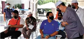  ?? — Bernama ?? Stay safe: Sulaiman (right) meeting with the people during an outreach programme at a vaccine centre in Masjid al-alami.