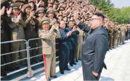  ?? REUTERSPIX ?? North Korean leader Kim Jong-Un waves to scientists and technician­s, who developed the Hwasong-12 missile, in this undated photo released by the Korean Central News Agency on Saturday.