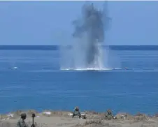  ?? — AFP photo ?? Philippine and US Marines watch as a projectile hits a target at sea during a live fire exercise against an imaginary ‘invasion’ force as part of the joint USPhilippi­nes annual military Balikatan drills on a strip of sand dunes in Laoag on Luzon island’s northwest coast.