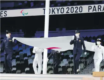  ?? THE ASSOCIATED PRESS ?? The Paralympic flag is taken down during the closing ceremony for the 2020 Paralympic Games at the National Stadium in Tokyo on Sunday.