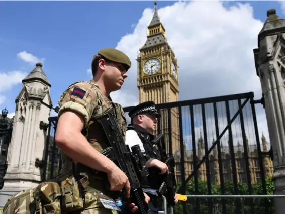  ??  ?? A soldier and armed policeman patrol along Whitehall near Downing Street yesterday